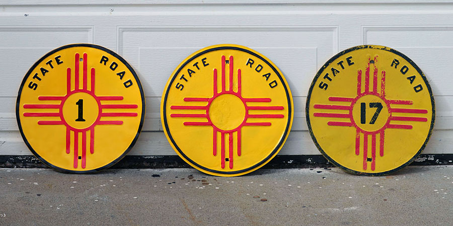 1926 specification reassurance markers, used between 1926 and 1931. The 17 has its original paint, and the other two are repainted. Due to weathering, the numbers on the left two were lost. The middle one has not yet received a new number. The digit "1" on the left sign was taken from the September, 1926 New Mexico Highways publication that introduced the zia markers for the first time.