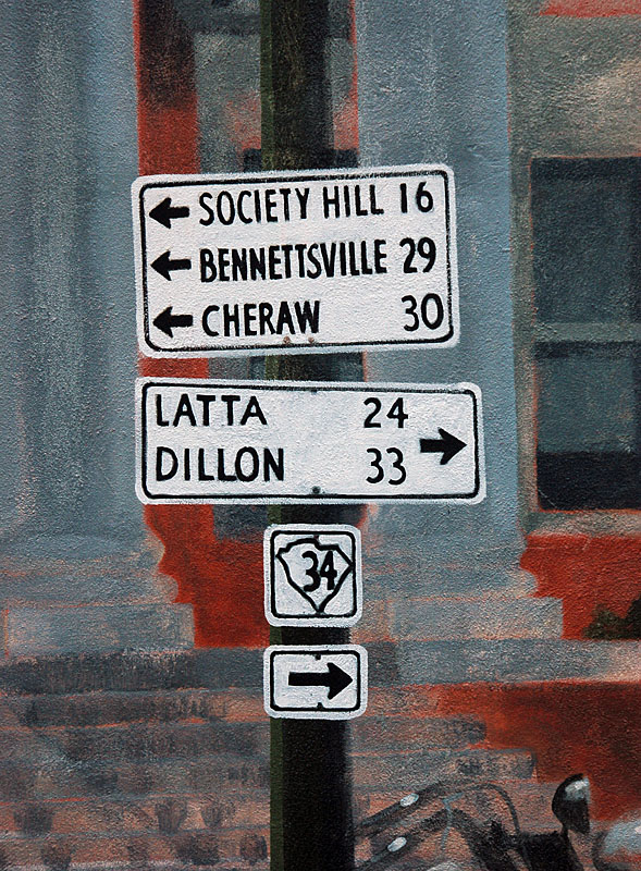 Painted old signs, including a 1930s highway marker, on the side of a building in Darlington.